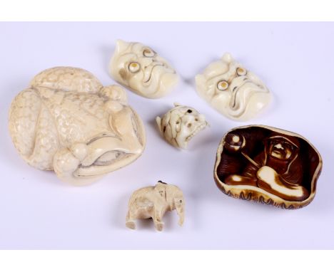 A Japanese carved ivory netsuke, formed as a man in a lily pad, three carved ivory miniature Noh masks and a carved ivory ele