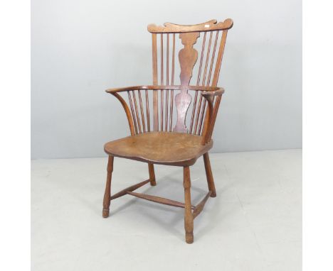 An antique elm-seated comb back Windsor elbow chair.Repairs visible to back splat and arm rail. Appears to have been cut down