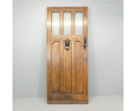 An Arts & Crafts panelled oak front door, from local private house, with cast iron lion mask door knocker and knight lock pla