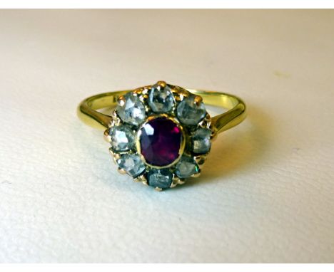 An 18ct. gold Dress Ring with an oval facet cut centre ruby surrounded by facet cut diamonds. 