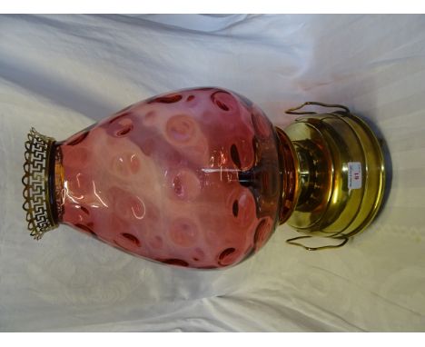 A brass Oil Lamp with a large dimpled cranberry glass shade.  19" (49cms) high. 