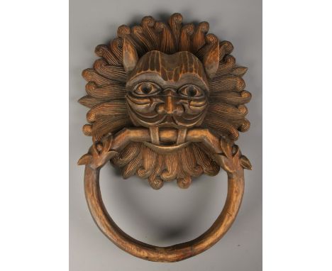 A carved wooden mask formed as a sanctuary door knocker. Signed to the back J. Sarabia. 41cm x 31cm.  