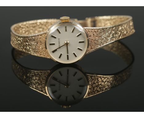 A Ladies 9ct Gold Tissot manual wind wristwatch, with baton marker dial, textured bracelet strap and hinged clasp. In working
