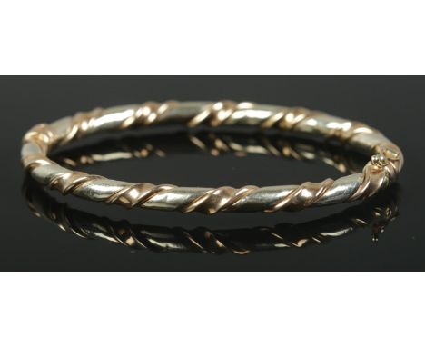 A 9ct Gold bangle with twisted decoration and hinged clasp. Total weight: 9.95g  