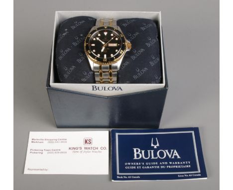 A boxed Gent's Bulova Marine Star quartz wristwatch, with French/English day and date windows on black dial. On two tone stai