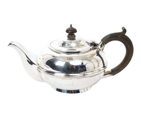 Early 20th century silver teapot of compressed bullet form, with hinged domed cover and fruitwood loop handle, on a circular 