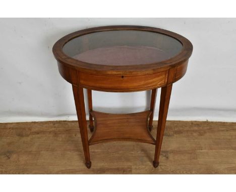 Edwardian inlaid satinwood bijouterie table of oval form with glazed hinged top and shaped shelf on square tapered legs, 64cm