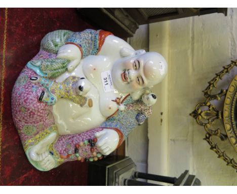 A Chinese Buddhist figure playing with two children, eight character impressed mark 21cm high