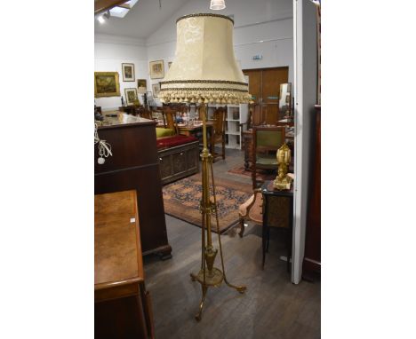 A height adjustable brass standard lamp with swags and fluted decoration the urn shaped base on tri-legs and melon fluted fee