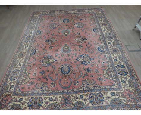 A pink ground carpet with substantial wear to one side, 247cm x 352cm