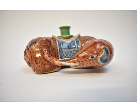 A Chinese ceramic taper stick holder in the form of an elephant, 6.5cm tall and 14cm longNo obvious damage but looks to have 
