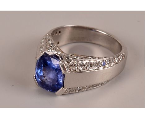 A fine modern platinum sapphire and diamond dress ring, the oval Ceylon blue stone in torsion setting having four tapering ro