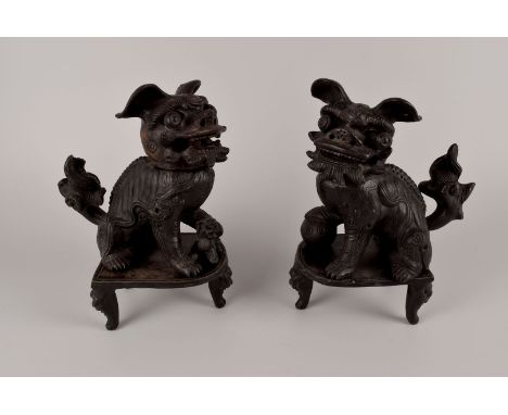 A pair of black ceramic temple dogs, or Shi, each with movable heads, eyes, and tails. Each standing on a three legged pedest