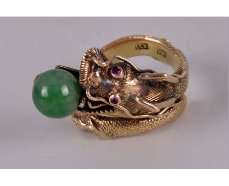 An interesting Chinese 14ct gold and jade dress ring, the mount in the form of a coiled dragon, having ruby set eyes and hold