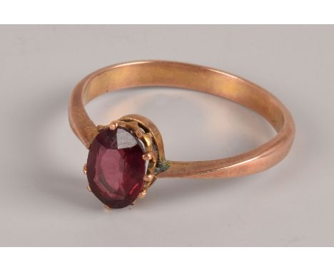 A vintage gold and garnet solitaire ring, having an oval stone in claws on unmarked band, in a Garlick of Newbury heart shape