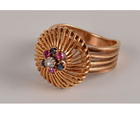 A retro continental yellow metal and gem set dress ring, the domed and pierced tablet set with red, blue and a clear stone, m