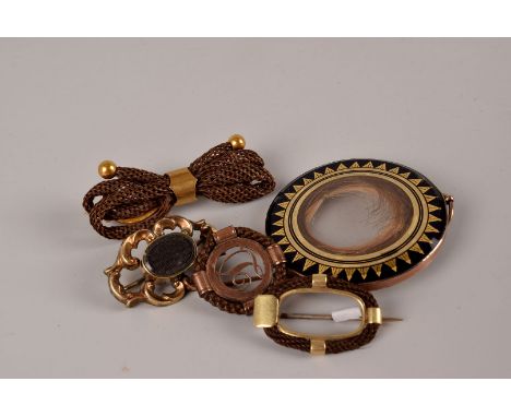 A group of four Victorian mourning brooches and a locket, the circular pendant with black enamel surround and lock of hair to