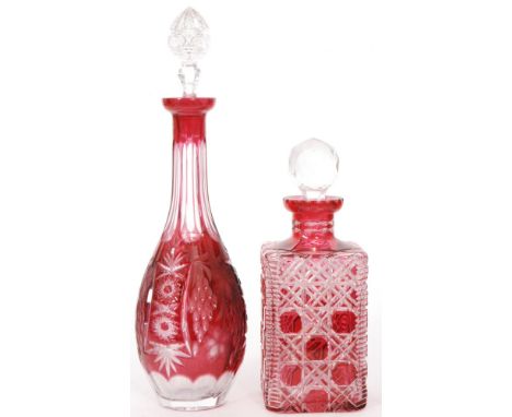 An early 20th Century glass decanter cased in cranberry over clear crystal, of square sleeve form below a clear lapidary stop