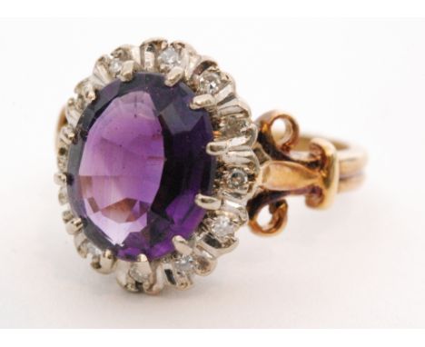 A modern 18ct hallmarked amethyst and diamond cluster ring, central amethyst within a diamond surround to scroll detailed sho