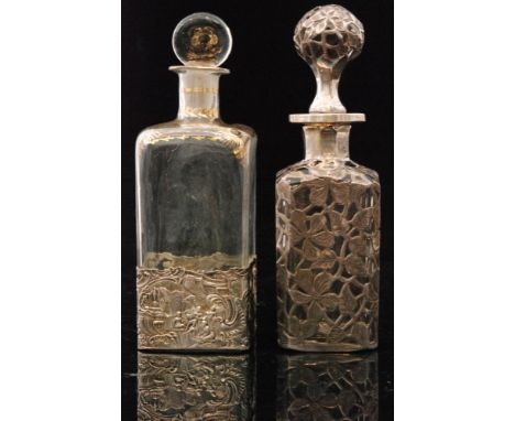 An early 20th Century glass cologne bottle of square sleeve form decorated with repeat flower motive silver overlay over the 