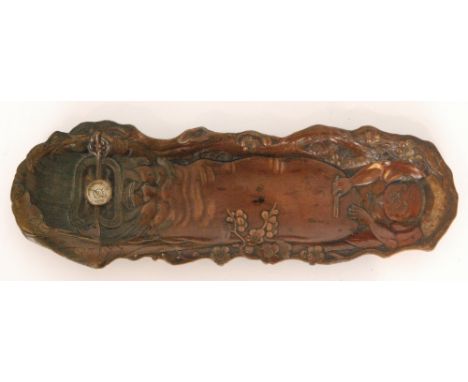 An early 20th Century elongated rectangular bronzed pen tray depicting Hotei with inset compass, all raised in four strut fee