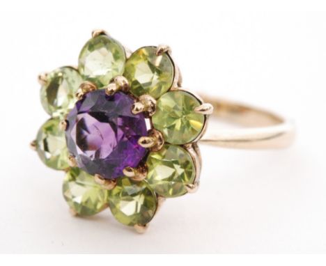 A modern 9ct hallmarked amethyst and peridot daisy cluster ring, central amethyst within seven stone peridot border, all to k