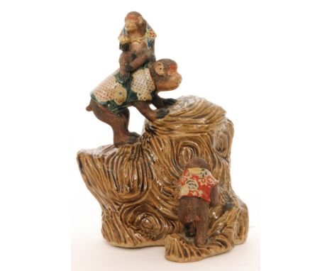 A Chinese clay model of a monkey and her two baby monkeys climbing a textured rock, each monkey wearing an enamel decorated p