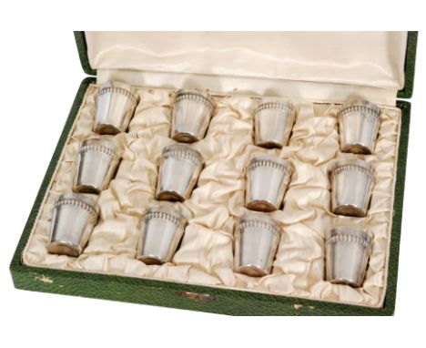 A cased set of twelve French silver plated cylindrical shot cups each with gadroon detail to border and stamped R.F. (12) 