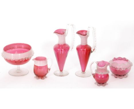 A group of late 19th Century Stourbridge cranberry glass comprising a pair of footed conical form jugs with applied clear cry