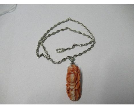 An Art Deco carved coral pendant, with a diamond to the centre of a green and black enamel suspension, all to a chain of chas