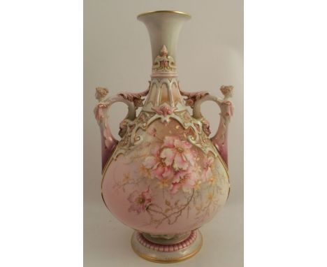 A Royal Worcester vase, decorated in turquoise, purple and pink with flowers, having figural handles, raised on a circular pe