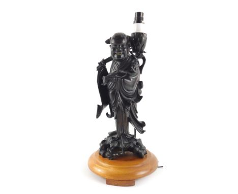 A Burmese hardwood carving, modelled as a Sage, converted into a table lamp, on a circular oak base, 46cm high overall.