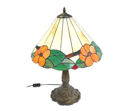 A Tiffany style table lamp, the conical shade decorated with orange flower heads amongst green leaves, against an off white g