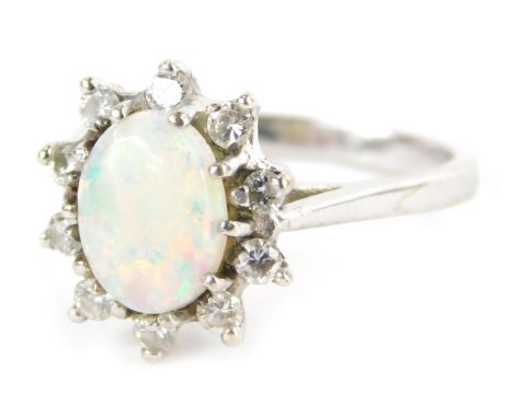 An opal and diamond dress ring, formed as a cluster with central oval opal in claw setting, surrounded by ten round brilliant