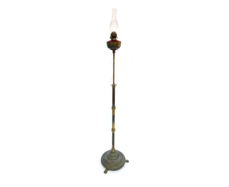 A 19thC brass oil lamp, with a cranberry glass reservoir, on tripod base, with glass funnel, 191cm high.