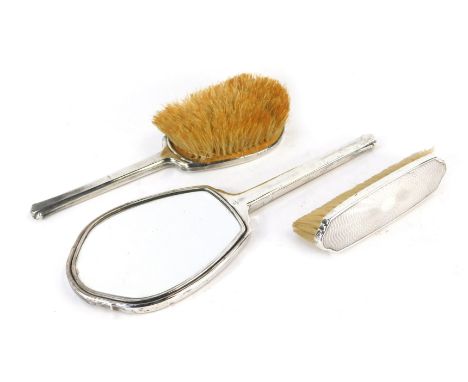 A George VI silver mounted dressing table set, comprising hand mirror, hair brush and clothes brush, each piece with engine t