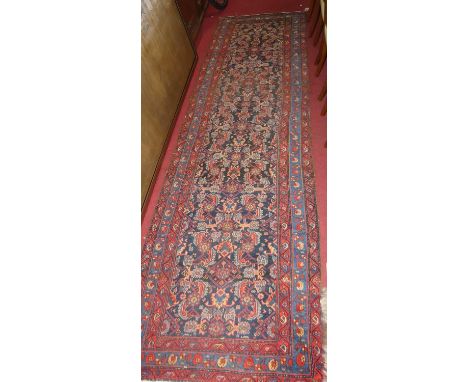 A Persian woollen blue ground Tabriz long hall runner, the floral geometric central ground within conforming tramline borders