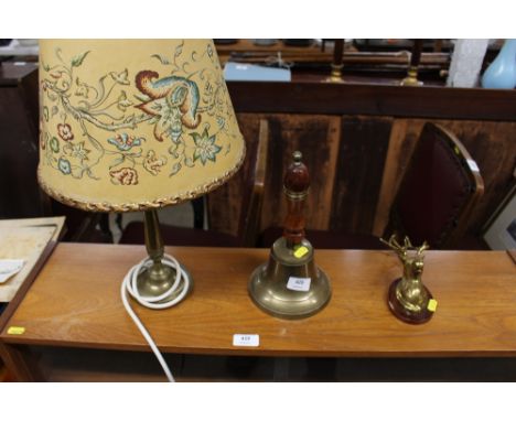 A brass bell; a brass stag head ornament; and a brass table lamp