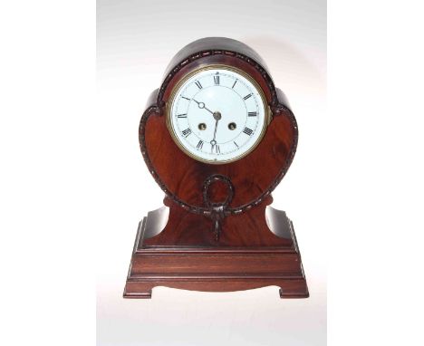 Shaped mahogany mantel clock raised on bracket feet with enamelled and Roman numeral dial.