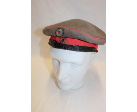A First War German grey and red cloth field cap with enamelled cockades, the liner dated 1914