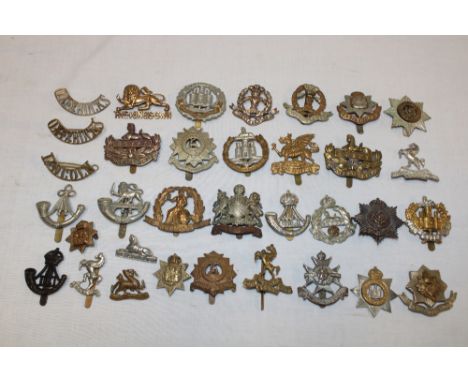 A selection of approximately 30 various military cap badges and insignia including the Cheshire Regiment, Essex Regiment, Glo