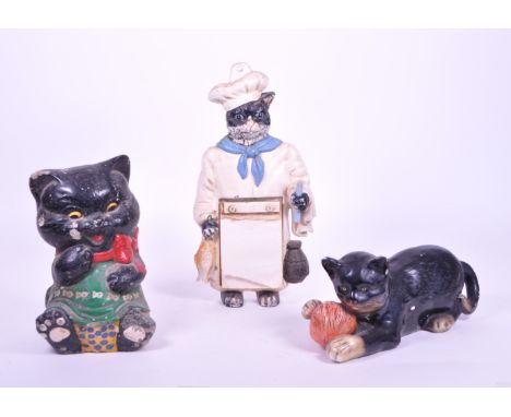 Three 20th century cat related figures. Comprised of a cast iron painted wall hanging chef cat memo board with pad and pencil