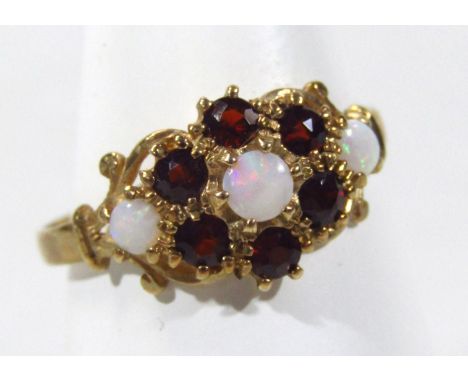 A ladies 9ct gold opal and garnet dress ring, florally set on part pierced fancy shank, size P, 2g all in. 