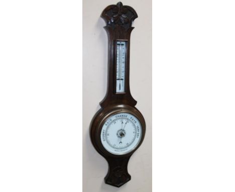 A 20thC stained oak banjo barometer and thermometer, in carved scroll and floral case, with 16cm dia. aneroid barometer surmo
