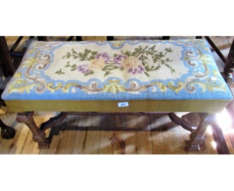 An oak framed duet stool with floral tapestry upholstery.