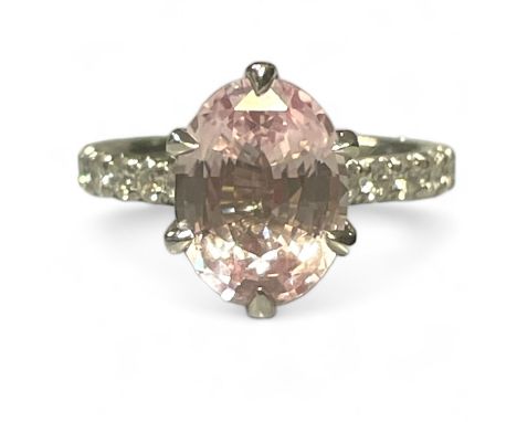 A 3.76 carat Padparadscha Sri Lankan pink sapphire ring, with a GIA origin report. The oval step cut stone is assessed by the