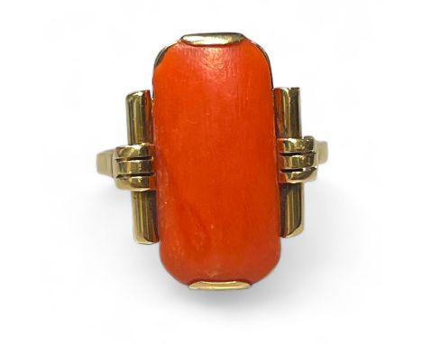 An Art Deco style coral panel ring. In yellow precious metal stamped "14ct" and "585" to the outside of the shank and testing