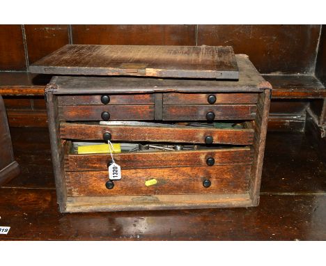 A DISTRESSED OAK ENGINEERS CHEST with seven various drawers containing various tools including micromitre's drill bits, etc