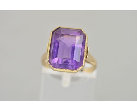 A 9CT GOLD AMETHYST RING, the rectangular amethyst collet set to the tapered shoulders and plain band, hallmarked Birmingham 
