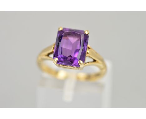 A 9CT GOLD AMETHYST RING, the rectangular amethyst within  a four claw setting to the openwork shoulders, length of amethyst 